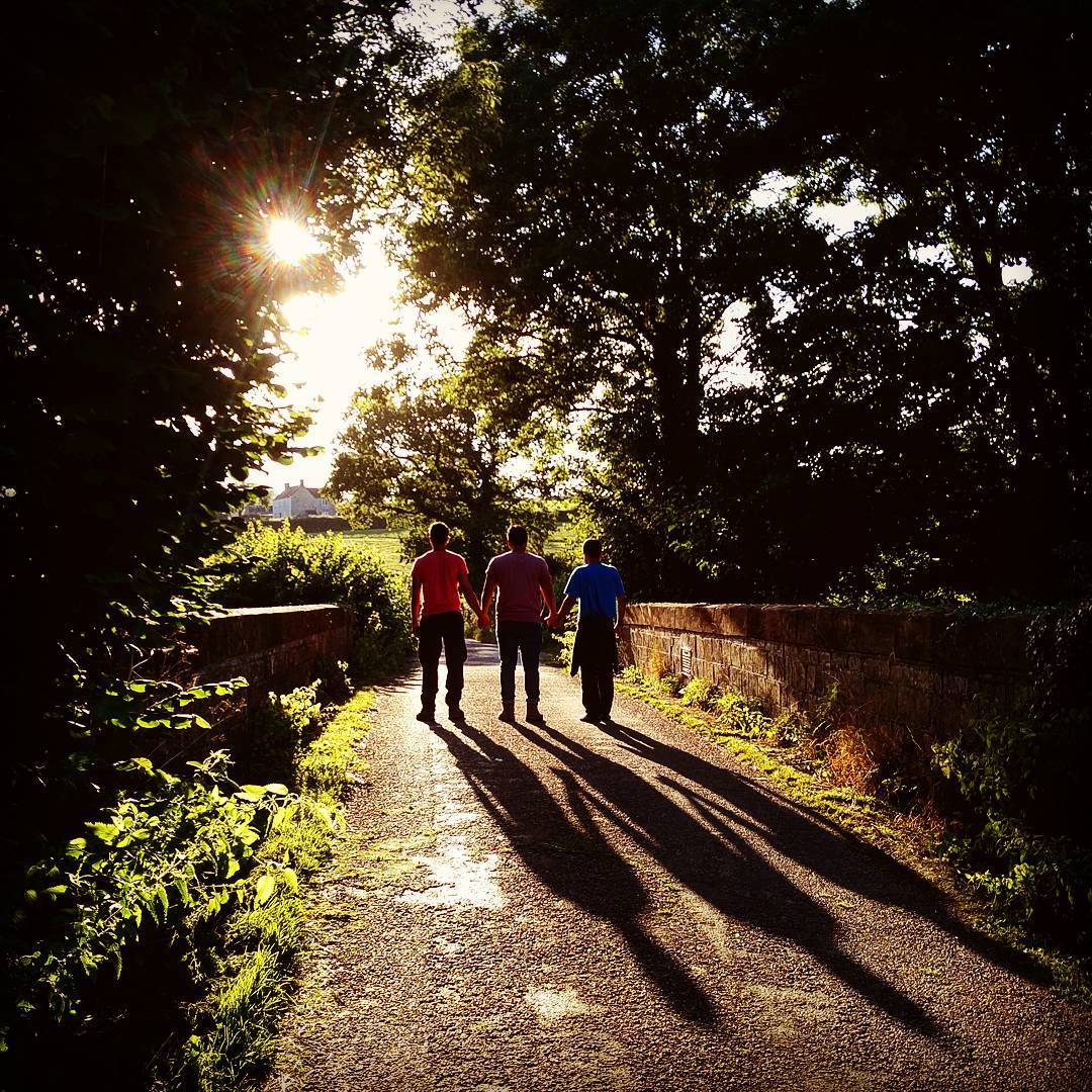 three men walking in the rays of the sun